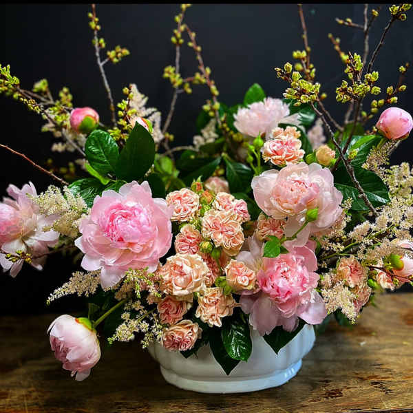 Pink peonies and small peach spray roses in a white bowl vase