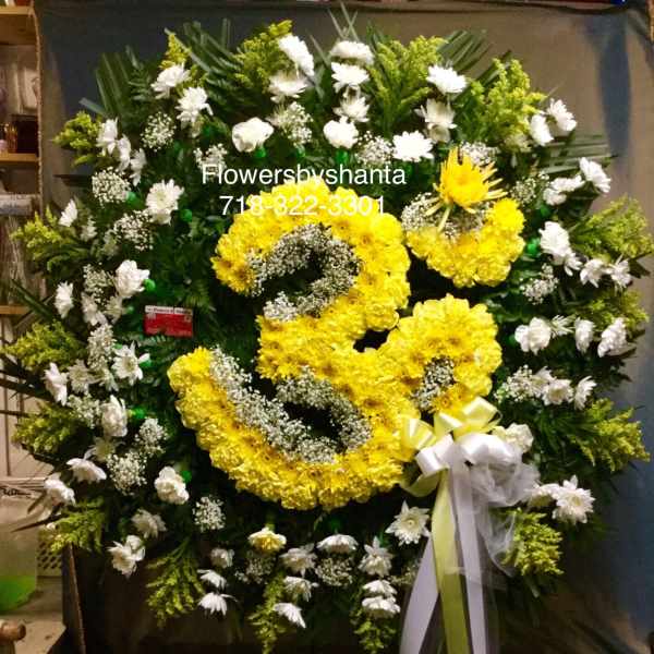 Large standing wreath of yellow and white flowers with ribbon