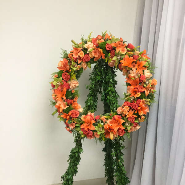 Large floral wreath on a stand with orange and pink blooms