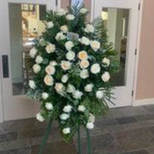 Standing spray of white roses and greenery on an easel