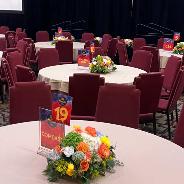 Round tables with small floral centerpieces and numbered signs in a banquet room