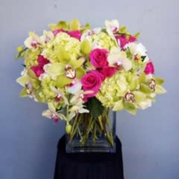 Bouquet of pink roses and pale green orchids in a clear vase