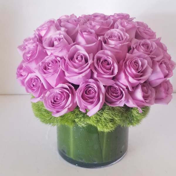 Pink rose bouquet in a green glass vase with a mossy base