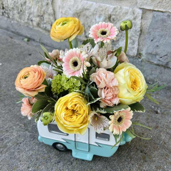 Bouquet of yellow and peach flowers in a small ceramic camper vase