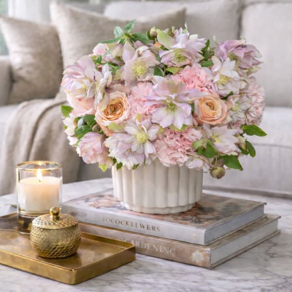 Blush and cream floral arrangement in a white vase on a table