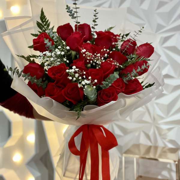 Bouquet of red roses wrapped in white paper with a red ribbon