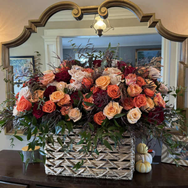 Large basket arrangement of peach, coral, and burgundy roses