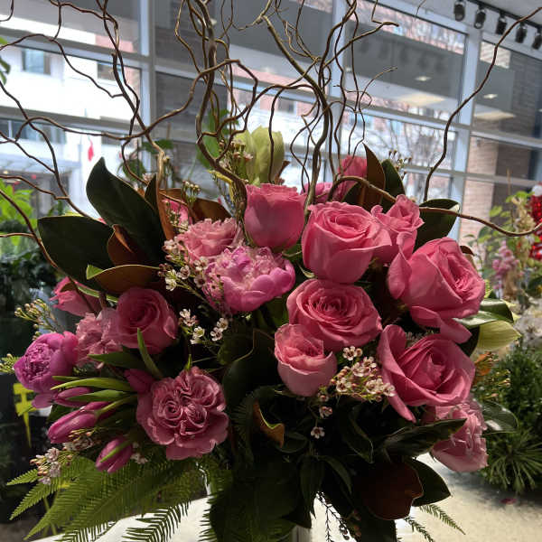 Pink roses and carnations in a glass vase with curly branches