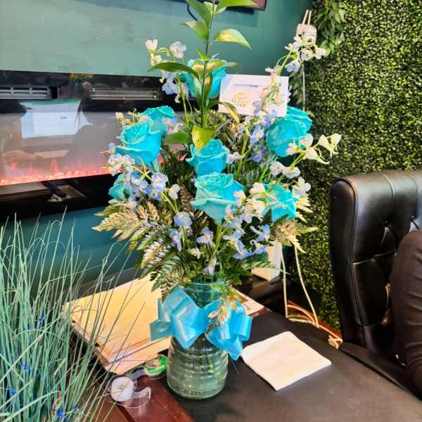 Tall blue rose arrangement in a glass vase with ribbon
