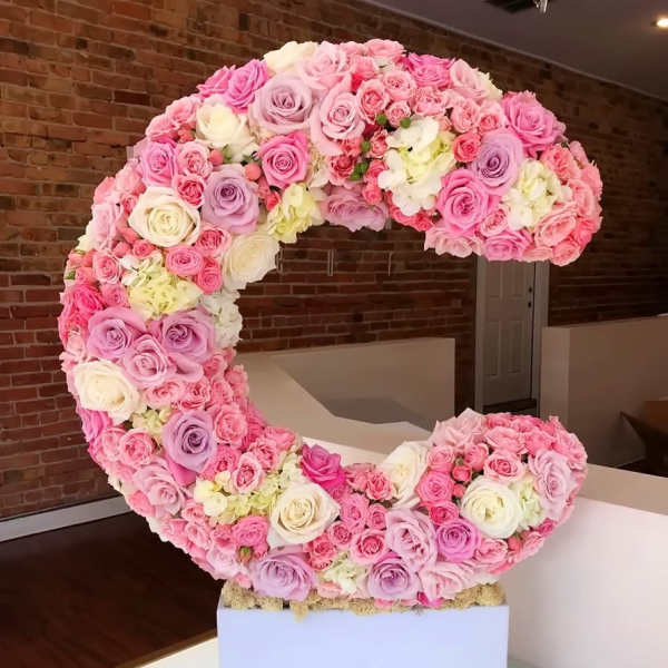 Large crescent-shaped arrangement of pink, lavender, and white roses