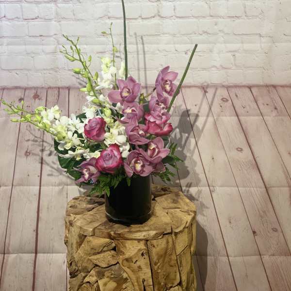 Pink orchids and roses arranged in a black vase