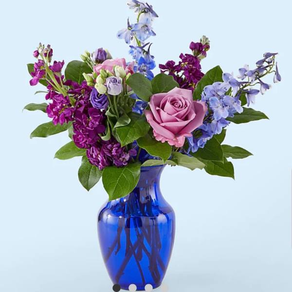 Mixed purple and pink flowers in a blue glass vase
