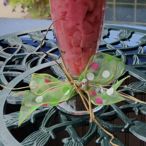 Milkshake-style floral arrangement with pink and white carnations, straws, and a polka dot ribbon butterfly.