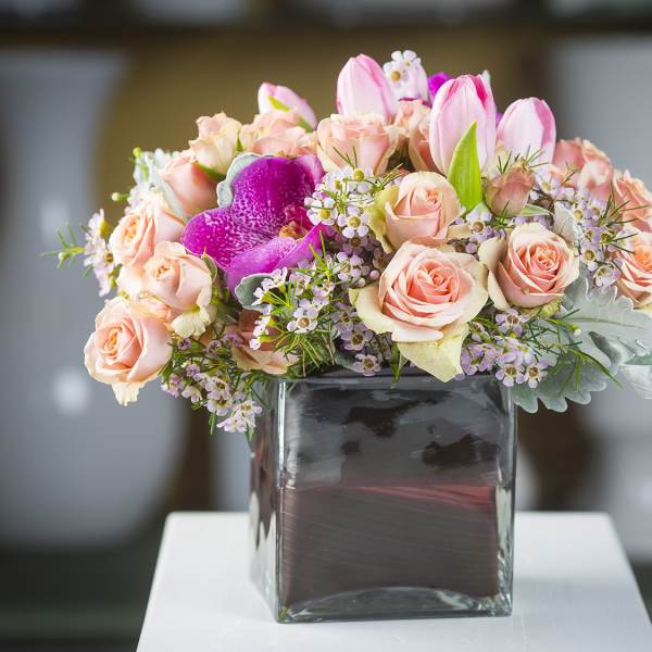Pink roses and tulips arranged in a square glass vase