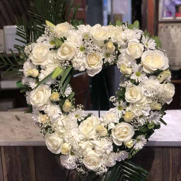 Heart-shaped white floral wreath with roses and daisies