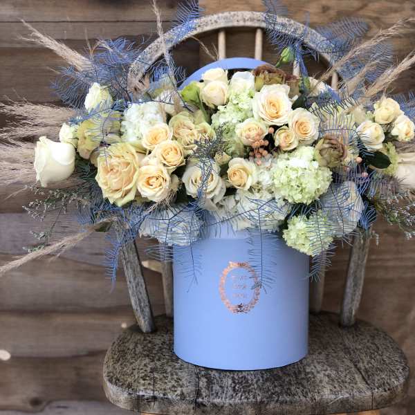 Bouquet of cream roses and pale hydrangeas in a blue box