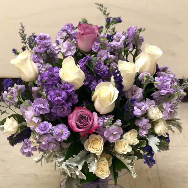 Bouquet of pink and cream roses with purple flowers in a glass vase