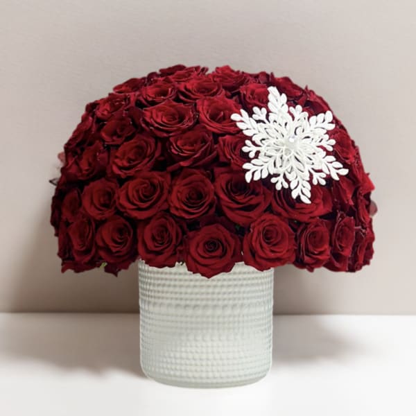 Red rose arrangement in a textured white vase with a white snowflake ornament