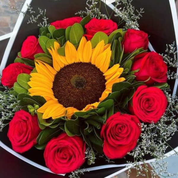 Bouquet of red roses surrounding a sunflower