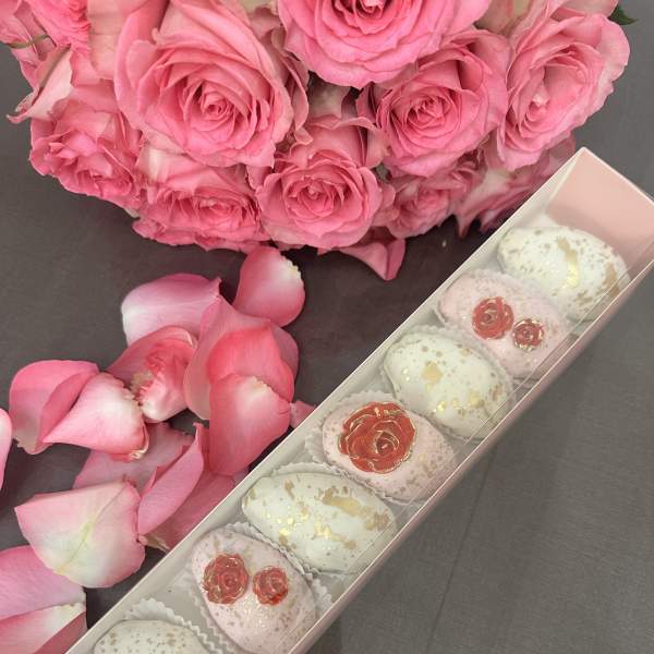 Pink rose bouquet with a box of decorated sweets and scattered petals