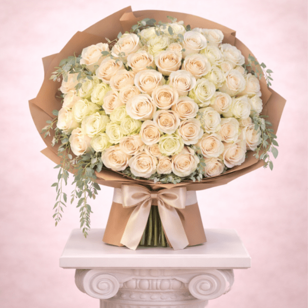 Large bouquet of cream and blush roses wrapped in brown paper with a satin bow