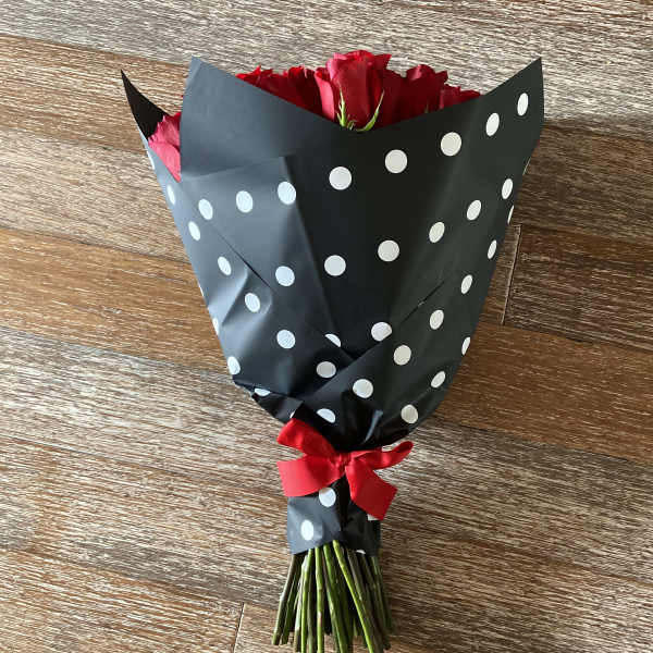 Bouquet of red roses wrapped in black polka-dot paper with a red ribbon