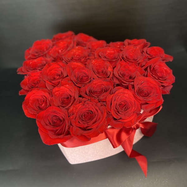 Heart-shaped box filled with red roses and a red ribbon