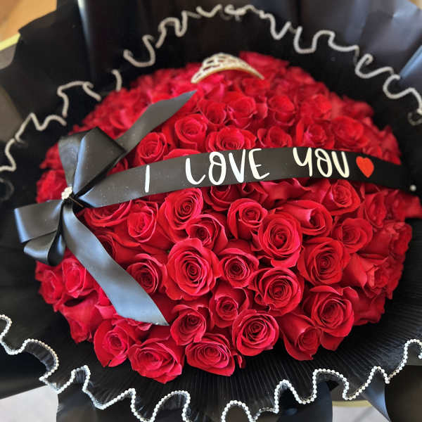Bouquet of red roses wrapped in black paper with a "I LOVE YOU" ribbon