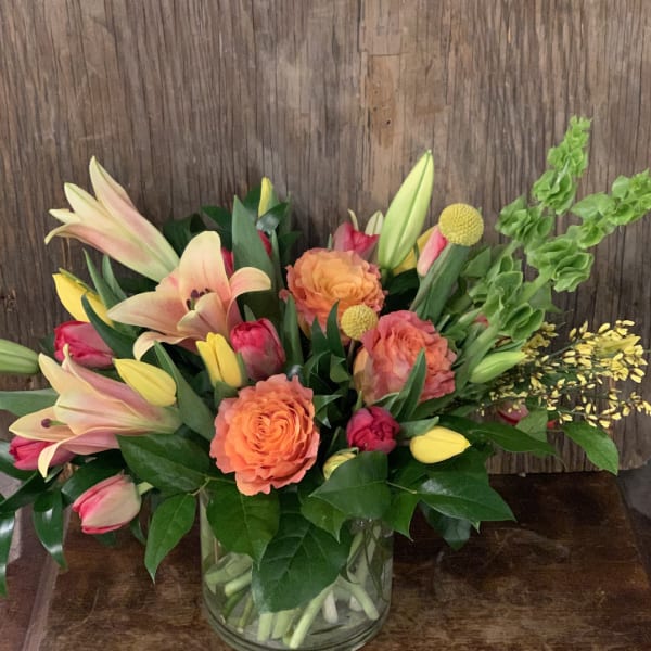 Mixed bouquet of lilies, roses, and tulips in a glass vase