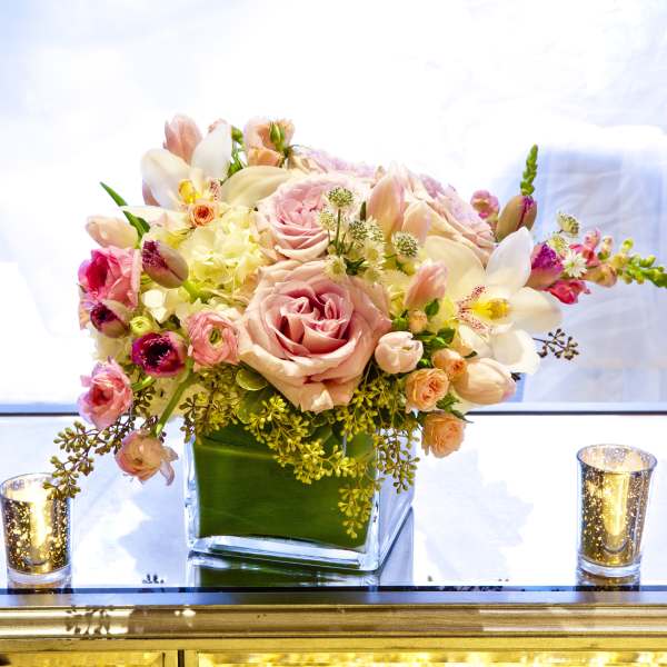 Pink and white floral arrangement in a square glass vase
