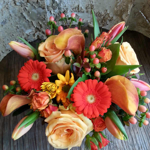 Mixed bouquet with peach roses, red gerberas, calla lilies, and pink buds