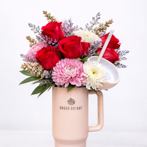 Bouquet of red roses and pink and white blooms in a blush tumbler vase