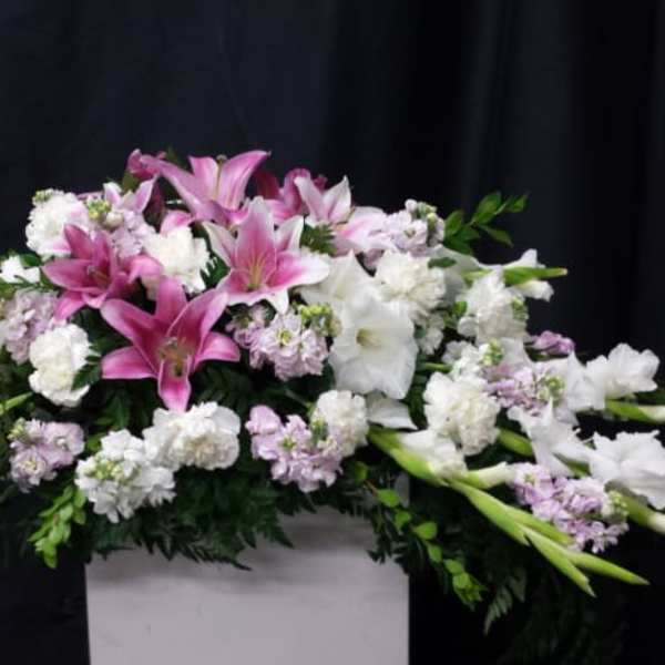 Pink and white lily arrangement with carnations in a white container