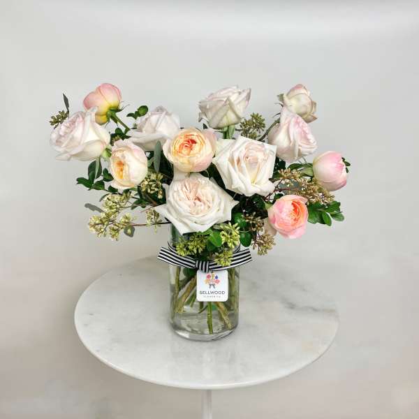 Blush and white roses arranged in a clear glass vase