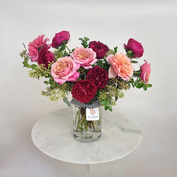 Pink and burgundy roses arranged in a clear glass vase