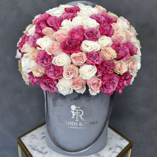 Round bouquet of pink and white roses in a gray hatbox