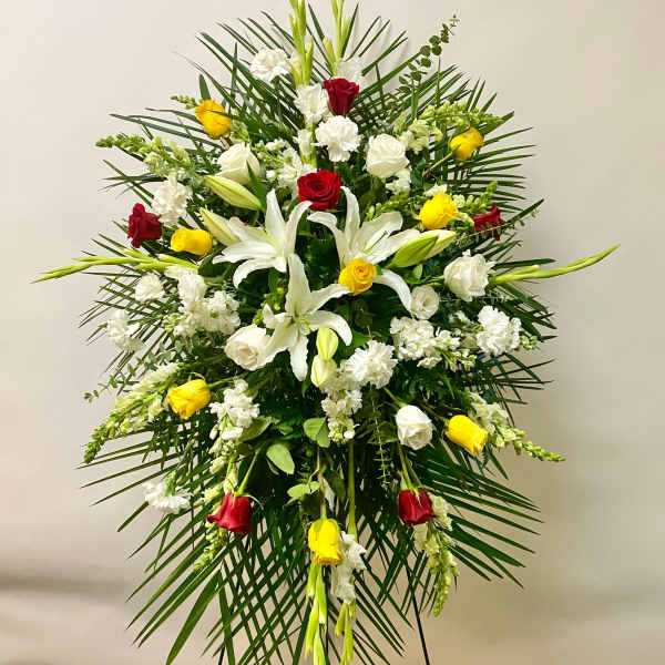 Standing floral spray with white lilies, roses, and red and yellow roses