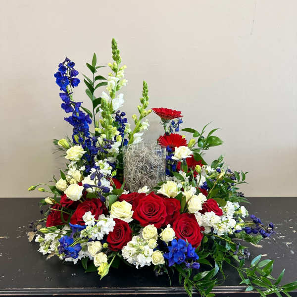 Red and white roses with blue and white flowers in a low centerpiece