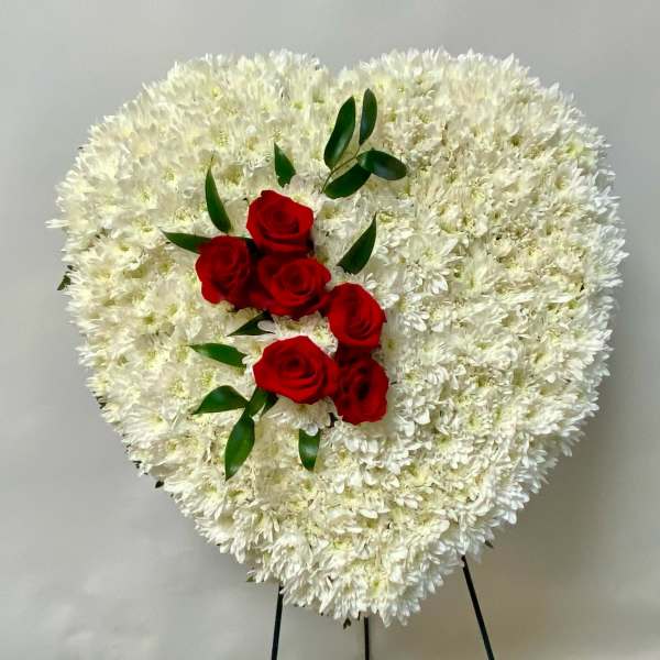 Heart-shaped white floral spray with red roses and greenery