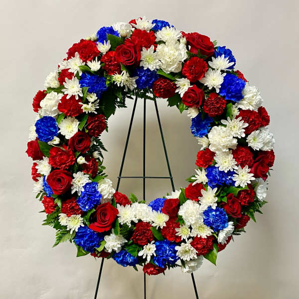 Red, white, and blue floral wreath on a black stand