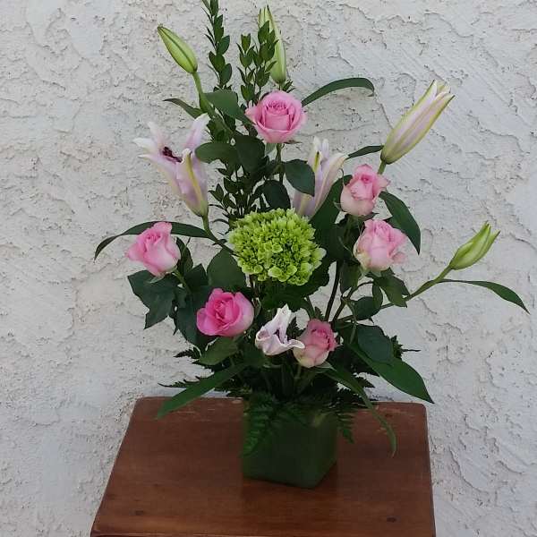 Pink roses and lilies arranged in a green vase