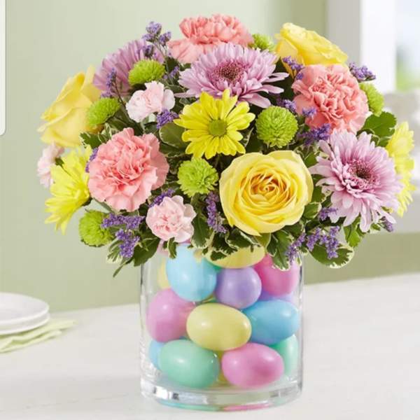 Mixed pastel bouquet in a clear vase filled with colorful eggs