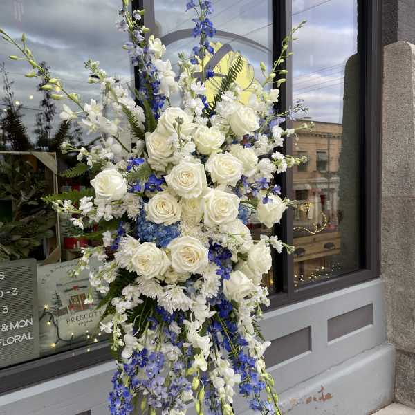 Tall floral spray with white roses and blue flowers on a stand