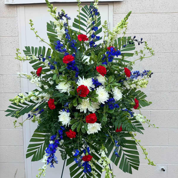 Large standing floral spray with red, white, and blue flowers on an easel