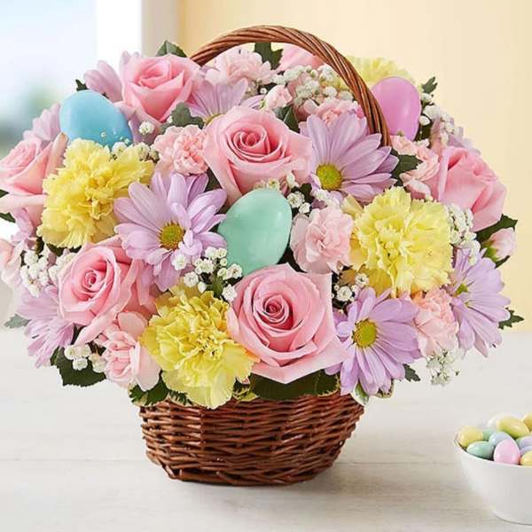 Basket of pink roses, daisies, and yellow carnations with pastel eggs