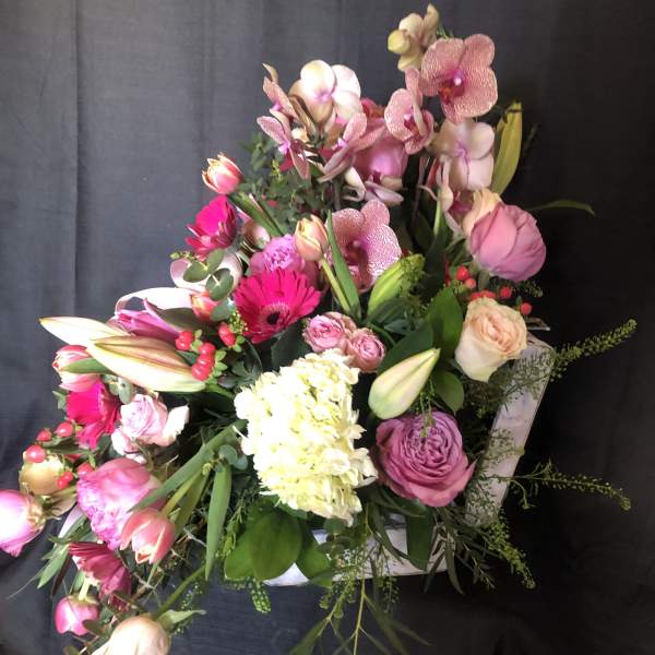 Asymmetrical pink and white flower arrangement in a white heart-shaped box