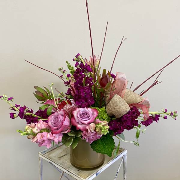 Pink and purple floral arrangement in a vase with ribbon accents