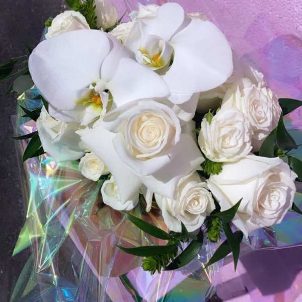 White roses and orchids wrapped in iridescent paper