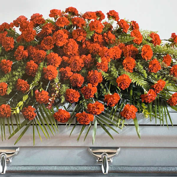 Orange carnation casket spray with palm fronds