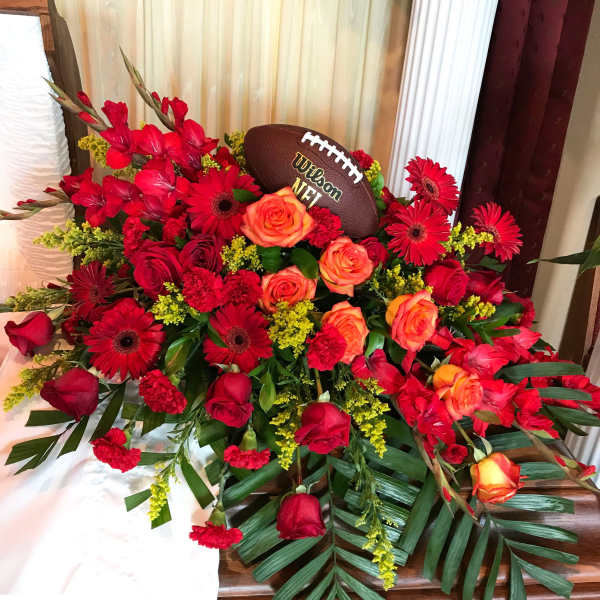 Red and orange floral arrangement with a football centerpiece
